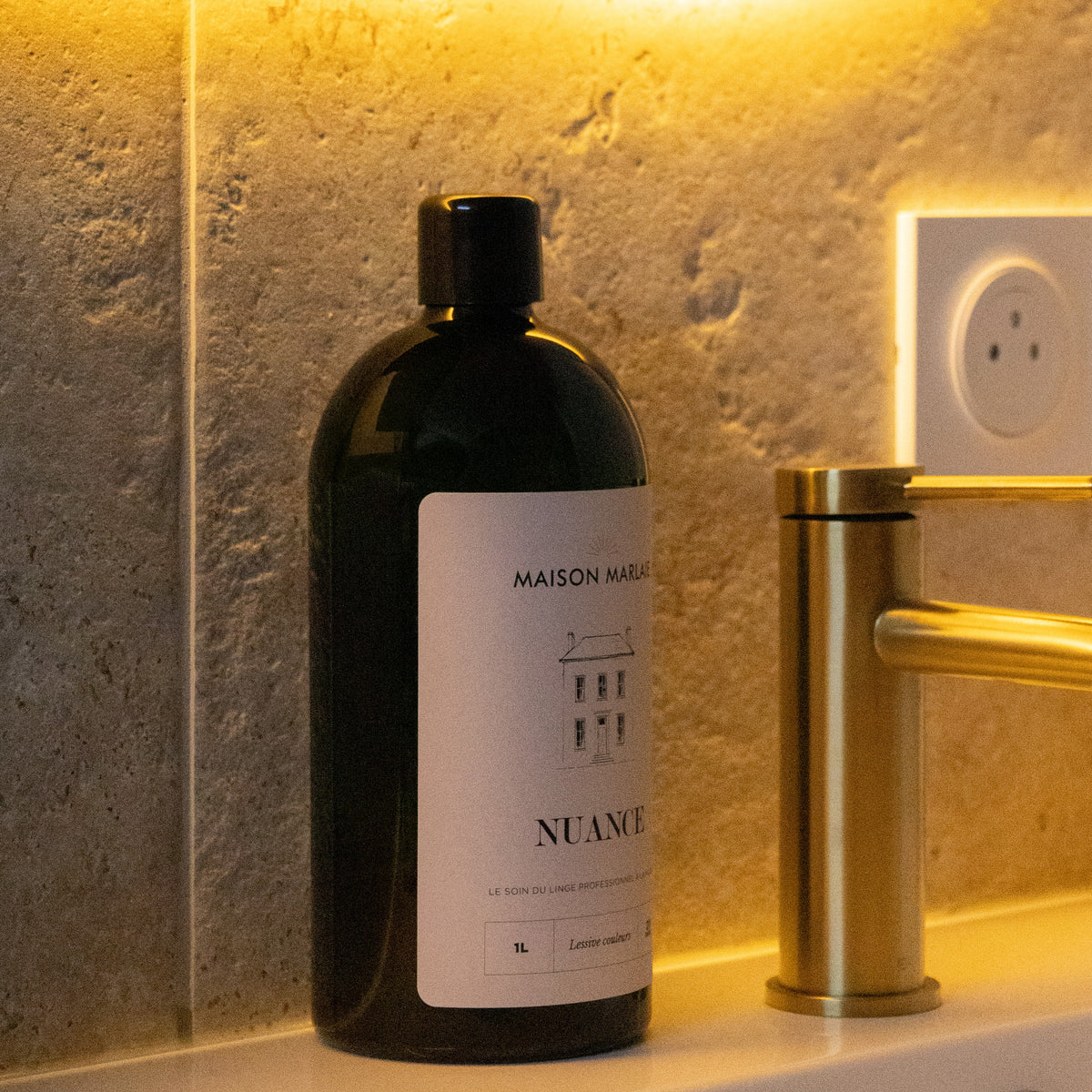 Stone and brass bathroom, NUANCE bottle by the basin