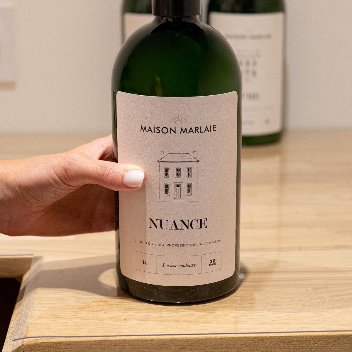 A hand placing the NUANCE bottle on a wooden surface